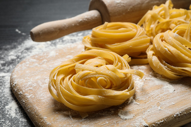 Photo of Tagliatelle pasta on wooden board, closeup view