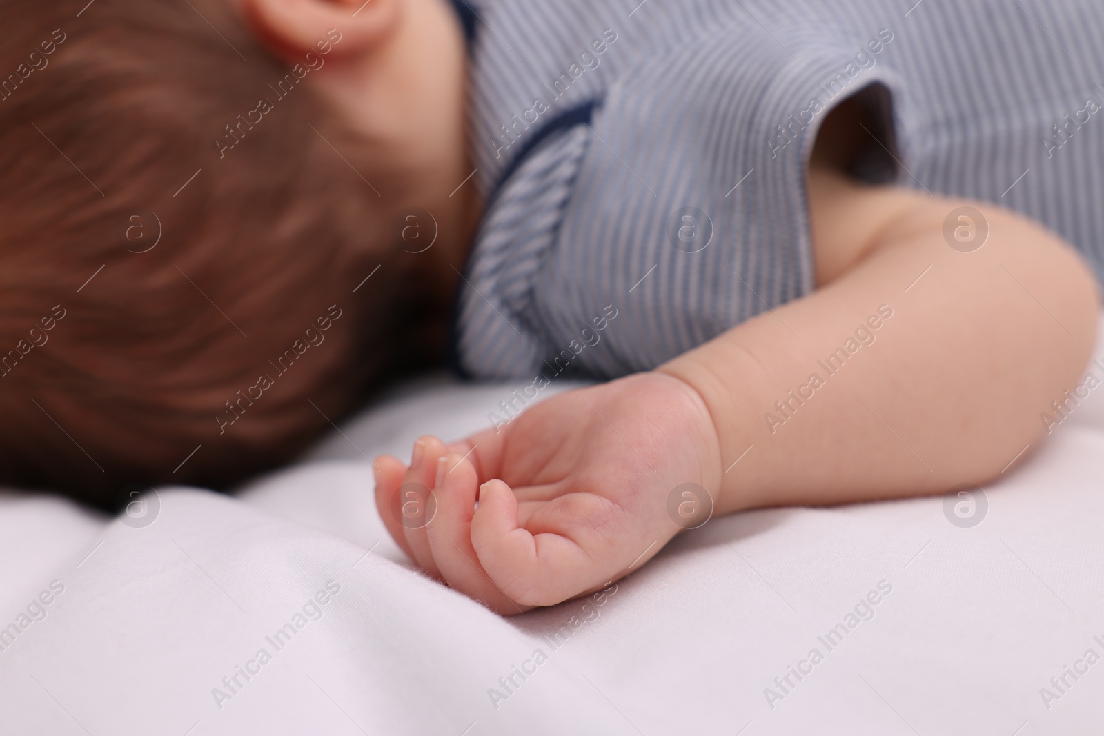 Photo of Newborn baby lying on white blanket, closeup