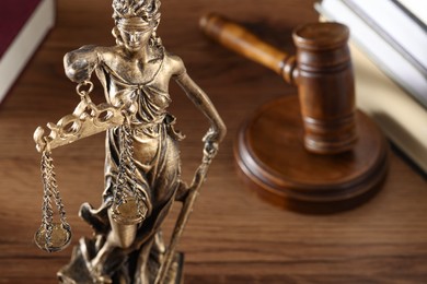 Photo of Symbol of fair treatment under law. Figure of Lady Justice, books and gavel on wooden table, closeup with space for text