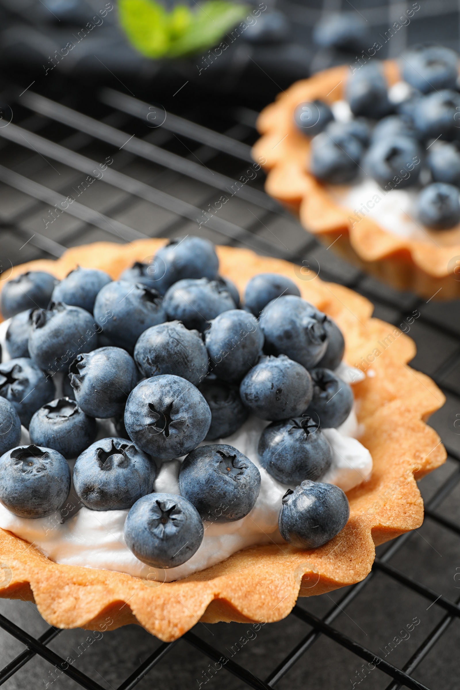 Photo of Delicious sweet pastry with berries on cooling rack, closeup