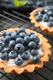 Photo of Delicious sweet pastry with berries on cooling rack, closeup