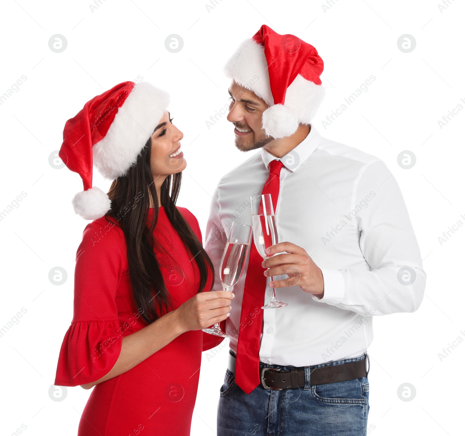 Photo of Lovely young couple in Santa hats with glasses of champagne on white background. Christmas celebration