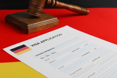 Photo of Immigration to Germany. Visa application form and wooden gavel on flag, closeup