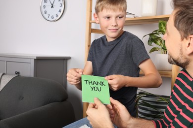Photo of Man receiving greeting card from his son at home