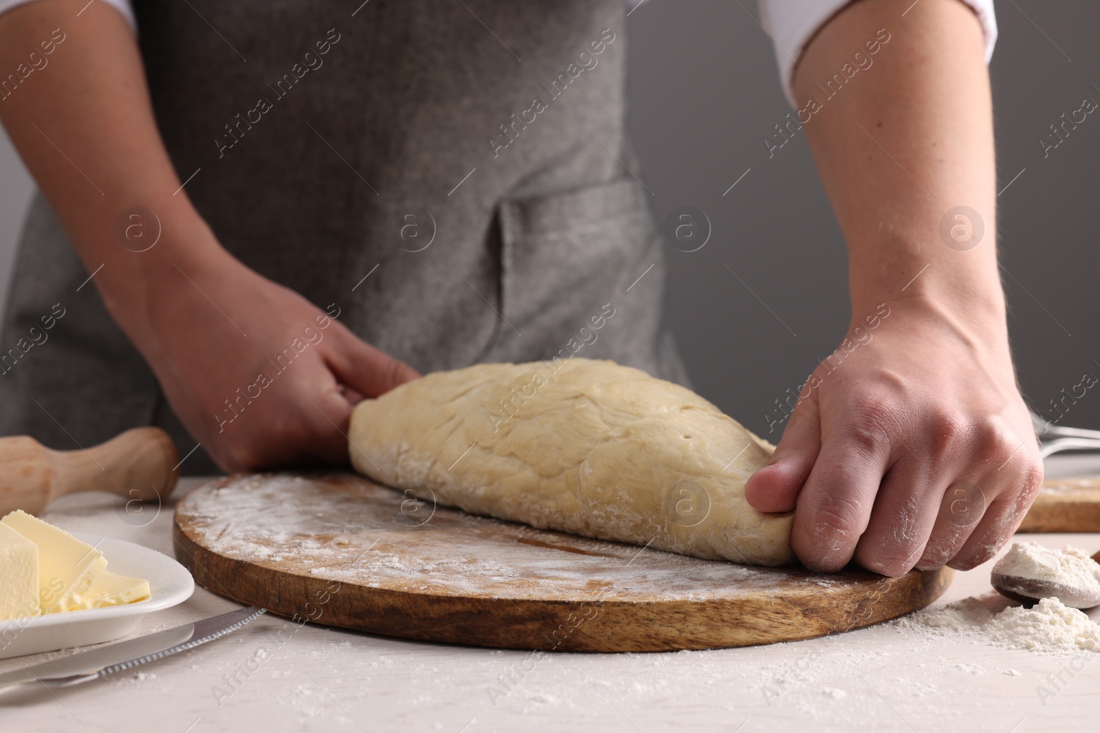 Photo of Man kneading dough at table near grey wall, closeup