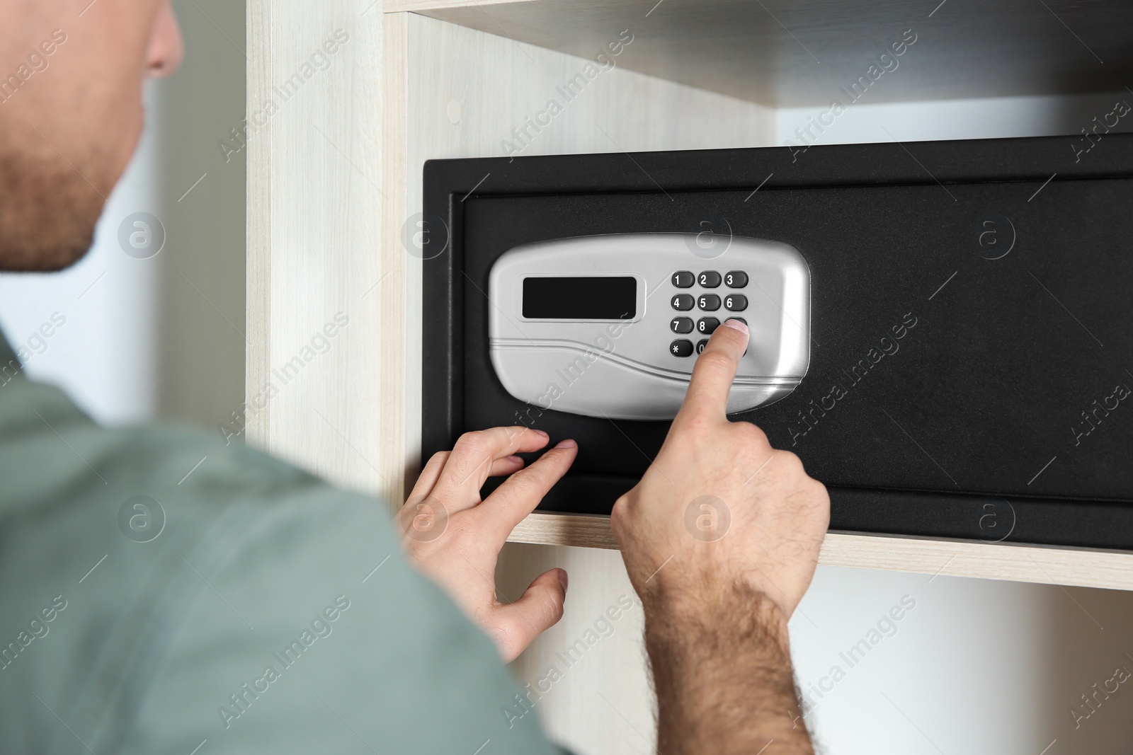 Photo of Man opening black steel safe with electronic lock at hotel, closeup