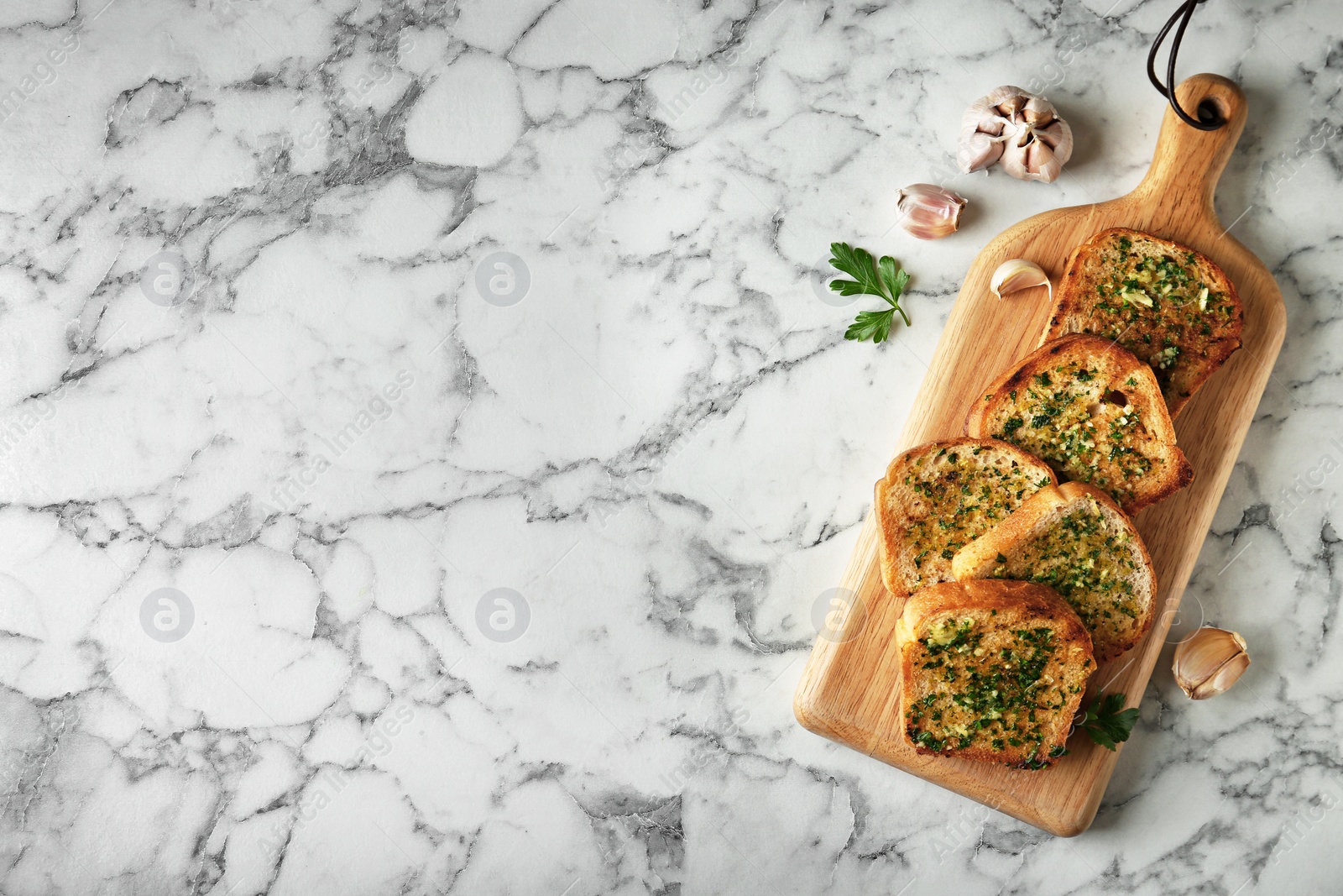 Photo of Slices of toasted bread with garlic and herbs on marble table, flat lay. Space for text