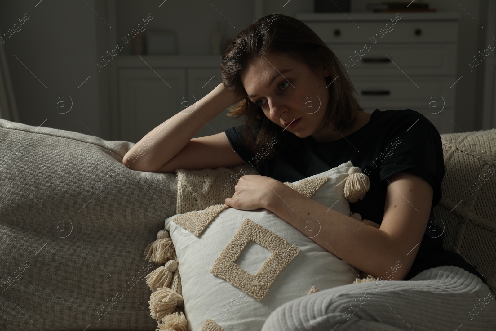 Photo of Sad young woman sitting on sofa at home