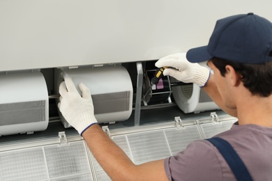 Photo of Male technician repairing air conditioner indoors