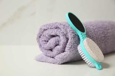 Photo of Pedicure tool with pumice stone and foot file near towel on white table, closeup