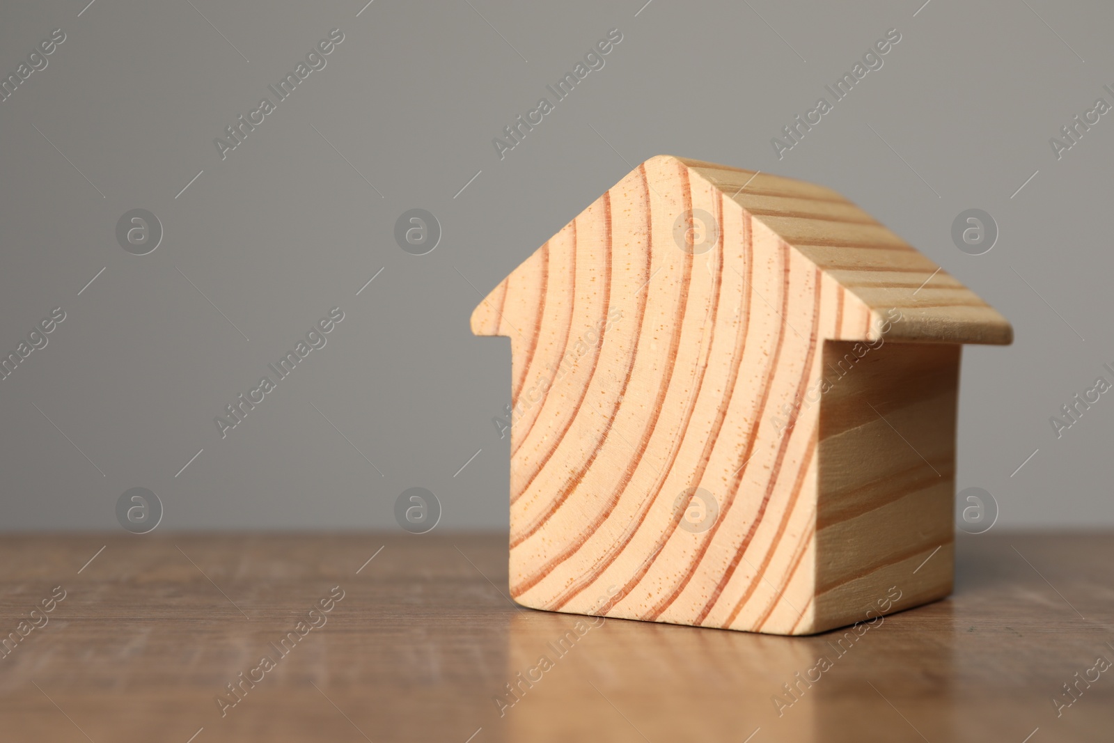 Photo of Mortgage concept. House model on wooden table against grey background, space for text