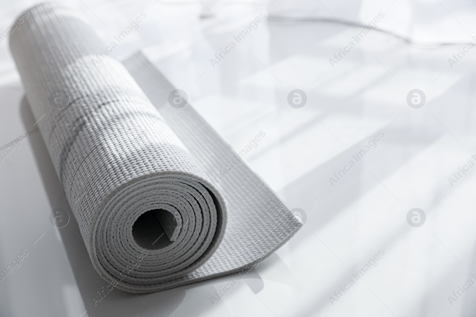 Photo of Rolled karemat or fitness mat on floor indoors, space for text