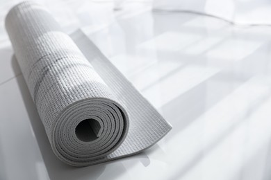 Rolled karemat or fitness mat on floor indoors, space for text