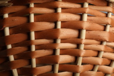 Handmade wicker basket made of natural material as background, closeup view