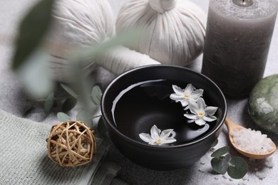 Beautiful composition with herbal massage bags, spa products and flowers on light grey table