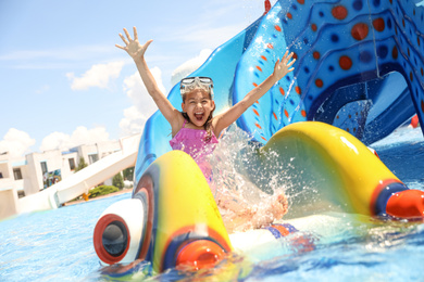 Photo of Little girl on slide at water park. Summer vacation