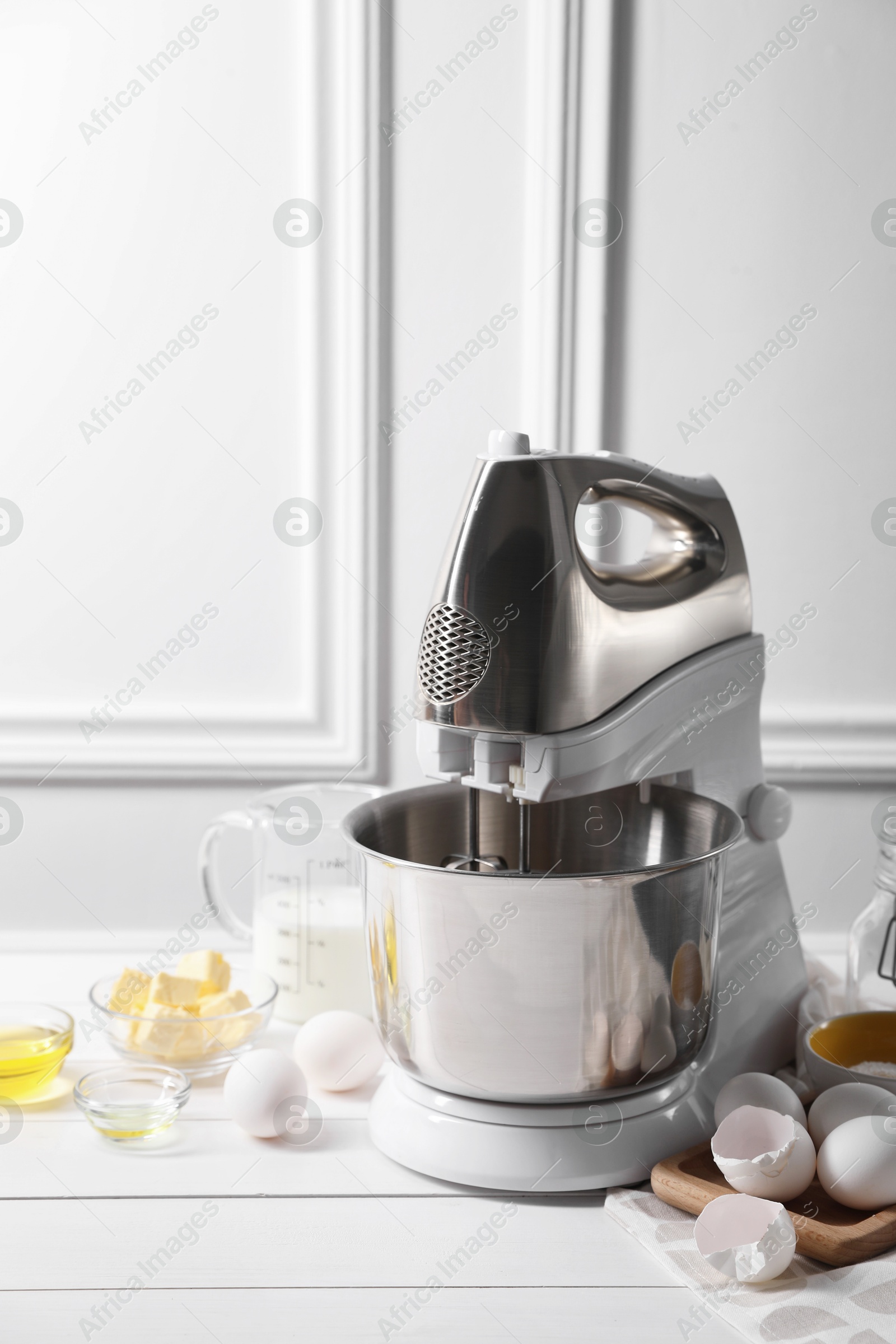 Photo of Modern stand mixer and ingredients for dough on white table indoors