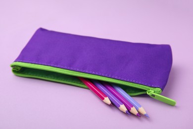 Many colorful pencils in pencil case on pink background, closeup