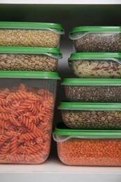 Photo of Plastic containers filled with food products in kitchen cabinet, closeup