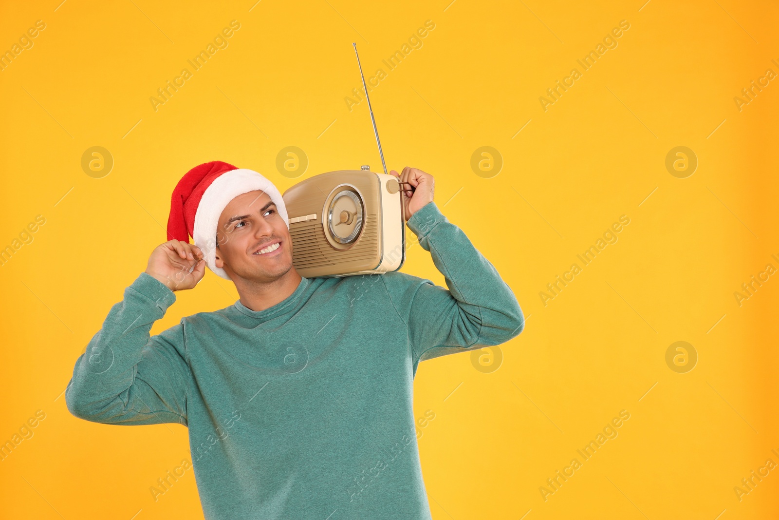 Photo of Happy man with vintage radio on yellow background, space for text. Christmas music