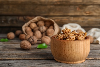 Photo of Bowl with tasty walnuts on wooden table. Space for text