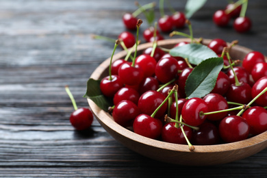 Photo of Delicious ripe sweet cherries on dark wooden table, closeup