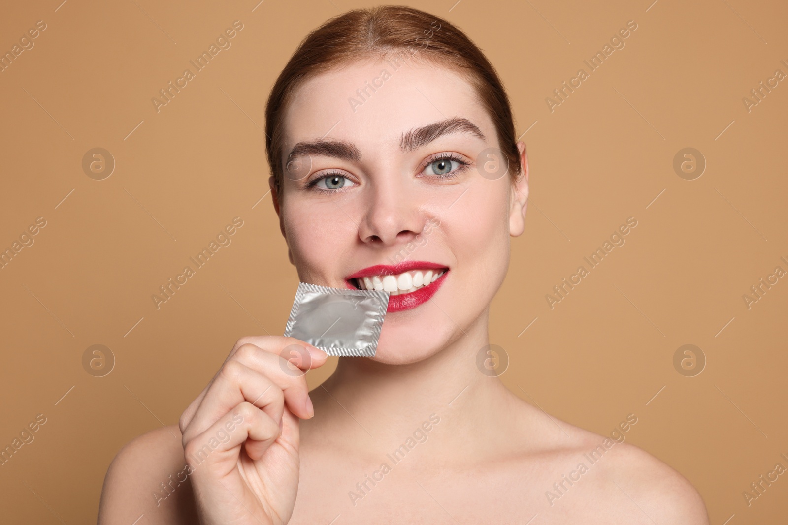 Photo of Woman holding condom on beige background. Safe sex