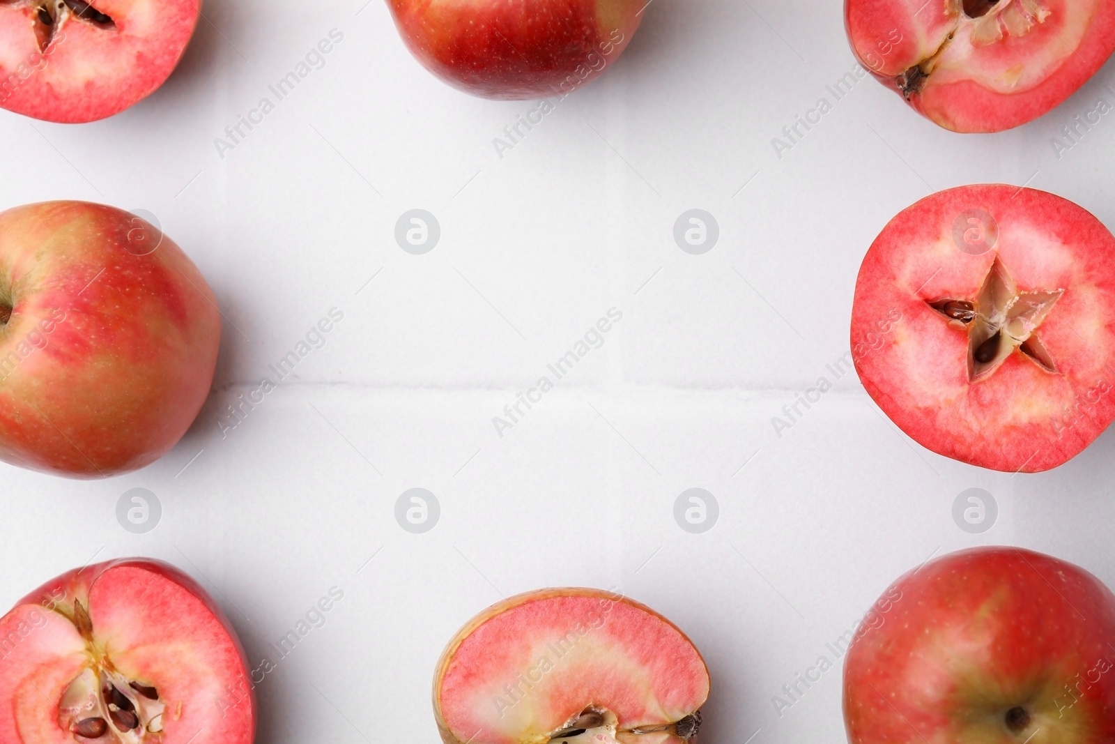 Photo of Frame made of tasty apples with red pulp on white tiled table, flat lay. Space for text