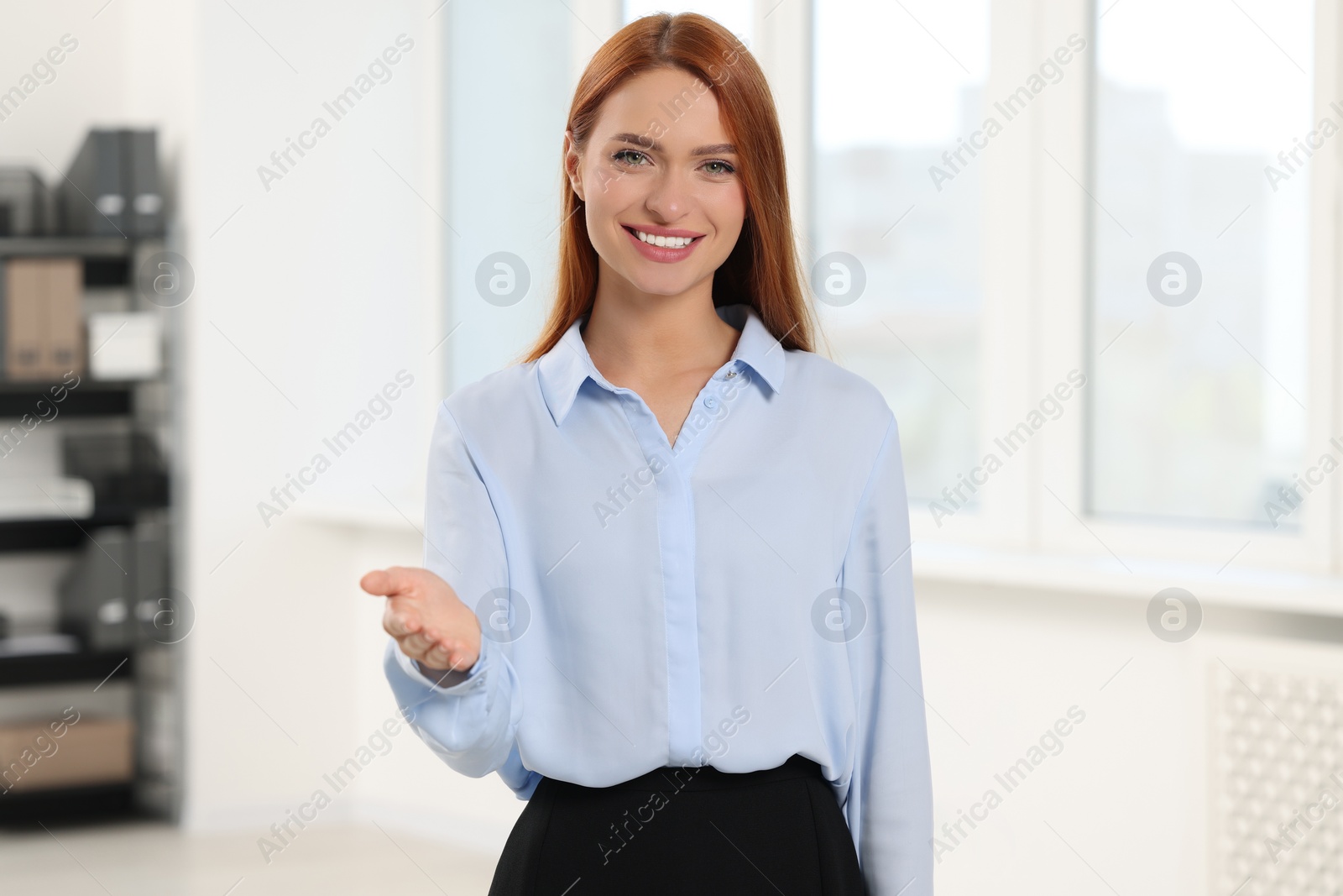 Photo of Happy woman welcoming and offering handshake in office