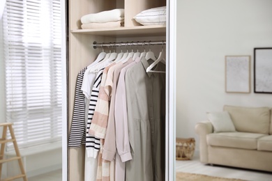 Photo of Wardrobe closet with different stylish clothes in room, closeup