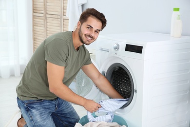 Photo of Young man using washing machine at home. Laundry day