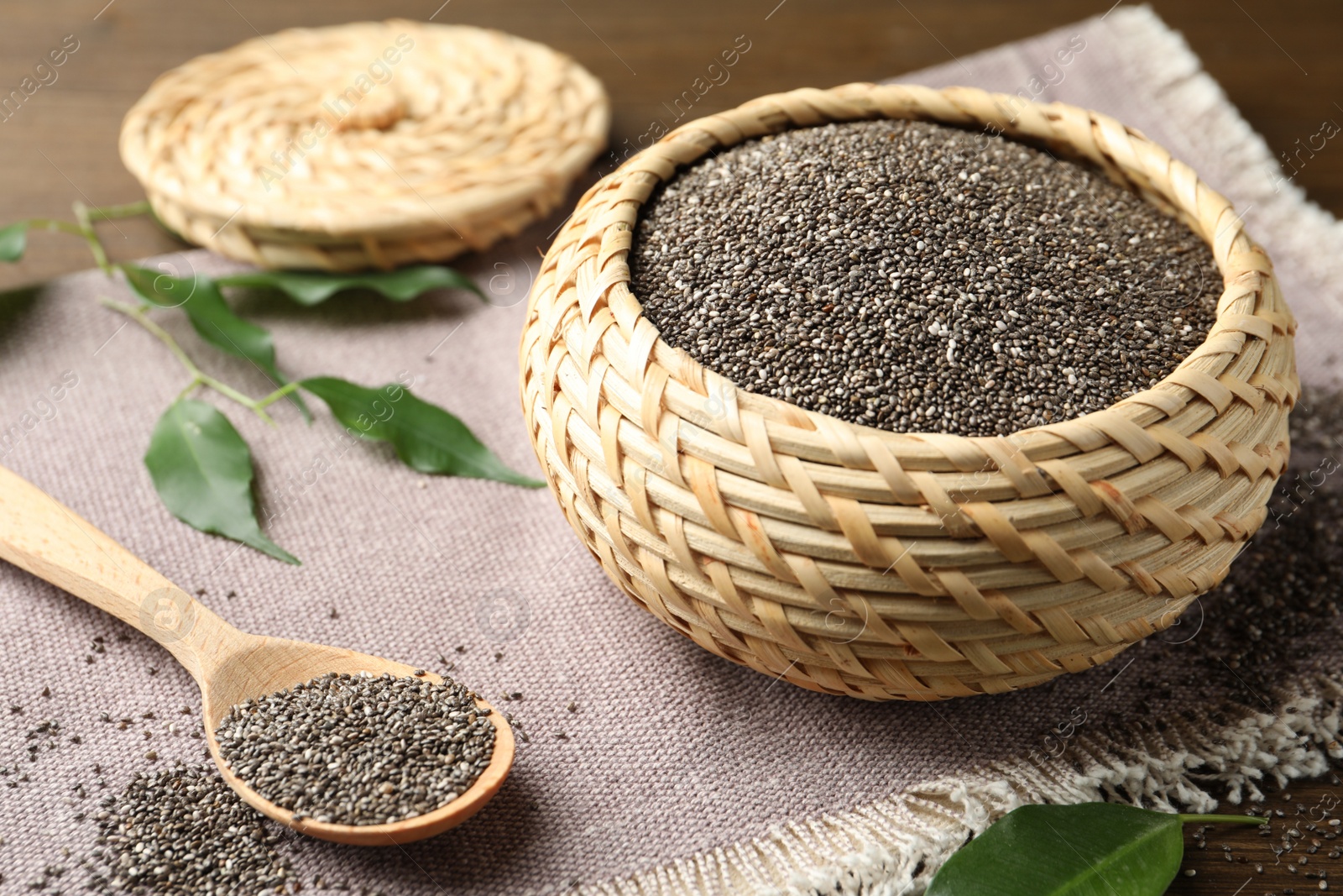 Photo of Wicker box and wooden spoon with chia seeds on table