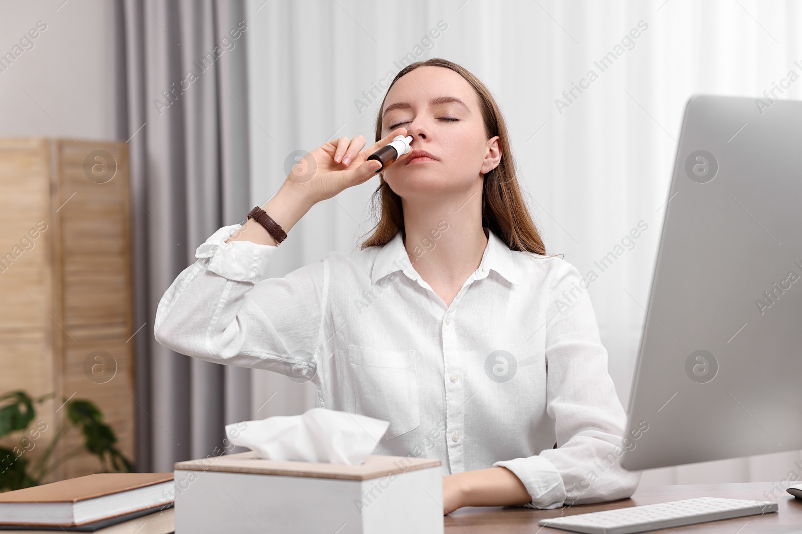 Photo of Medical drops. Young woman using nasal spray at home indoors