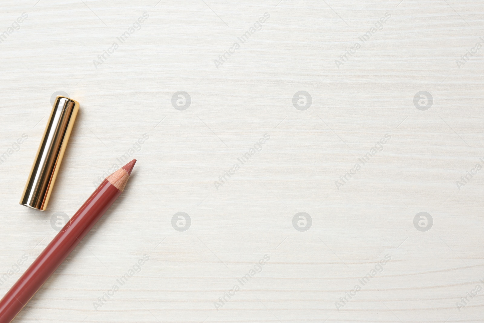 Photo of Lip pencil on white wooden table, flat lay. Space for text