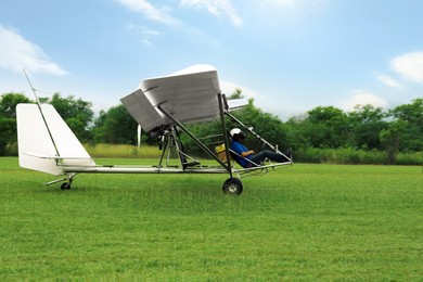 Photo of Man in light aircraft on green grass outdoors