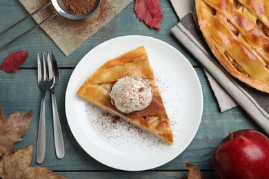Photo of Slice of traditional apple pie with ice cream served on blue wooden table, flat lay