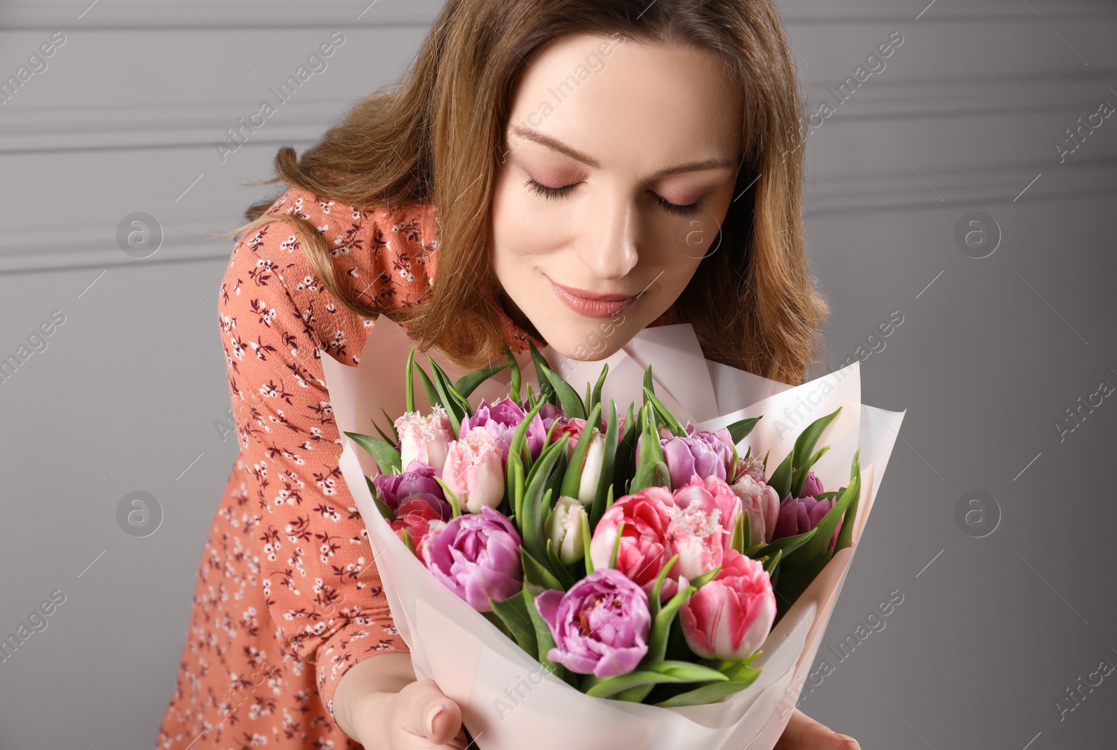 Photo of Happy young woman with bouquet of beautiful tulips indoors