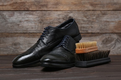 Photo of Men's leather shoes and cleaning brushes on wooden table