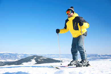 Young man skiing on hill, space for text. Winter vacation