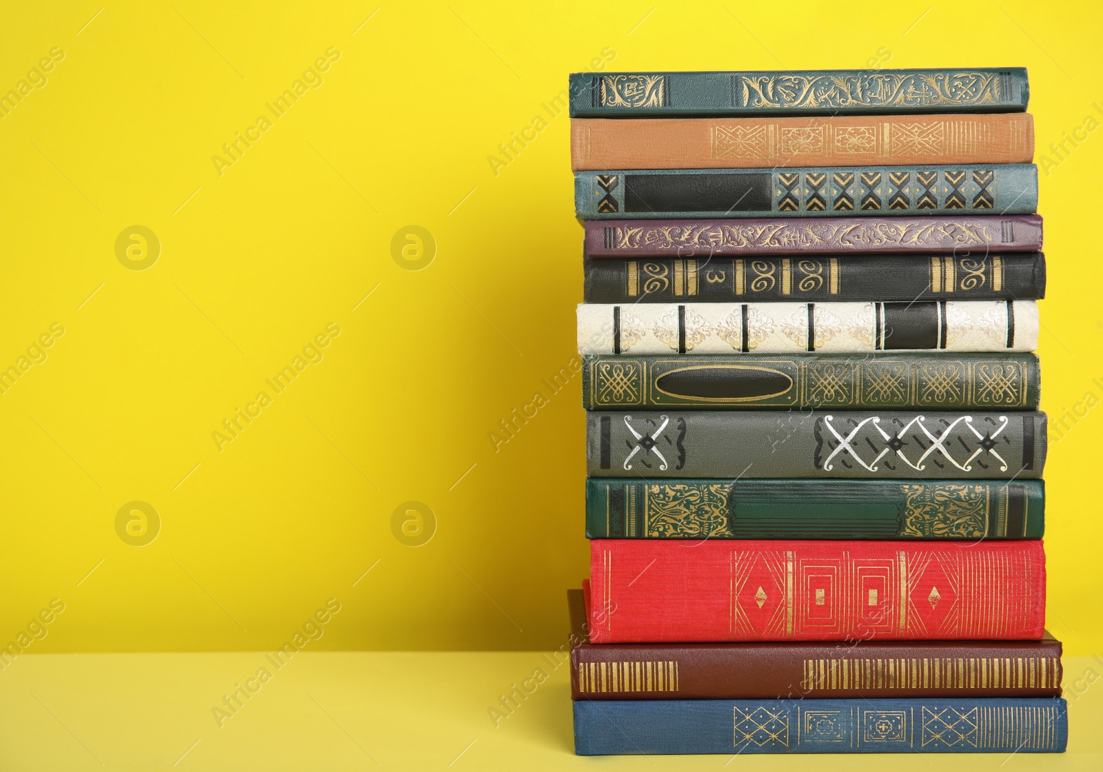 Photo of Stack of hardcover books on yellow background. Space for text
