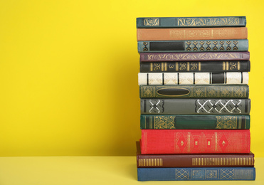 Stack of hardcover books on yellow background. Space for text