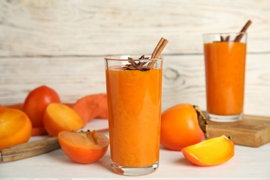 Photo of Tasty persimmon smoothie with anise and cinnamon on white wooden table