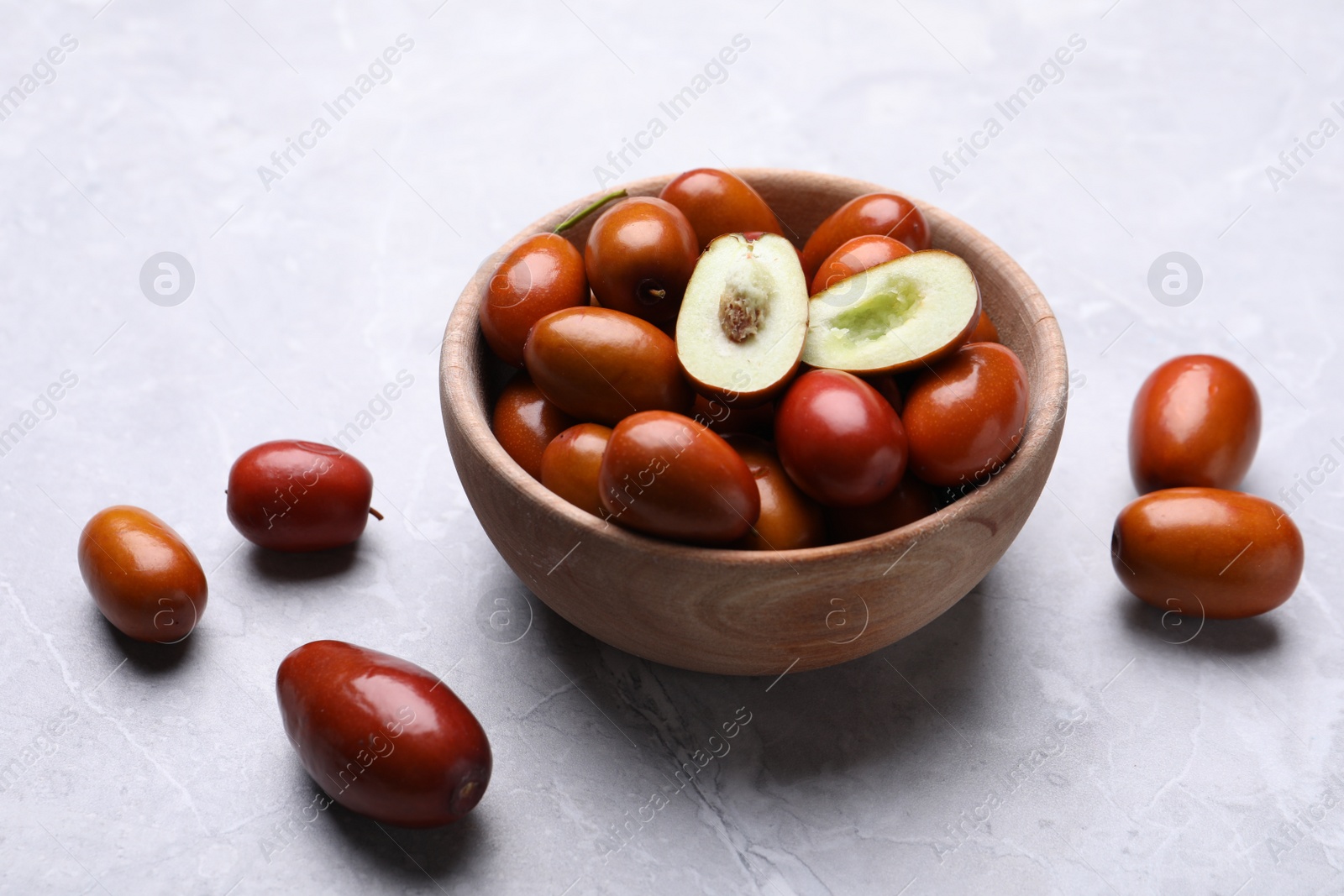 Photo of Fresh Ziziphus jujuba fruits with wooden bowl on light table