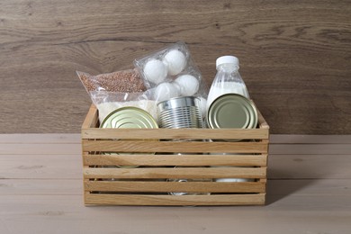 Donation box with food products on wooden table