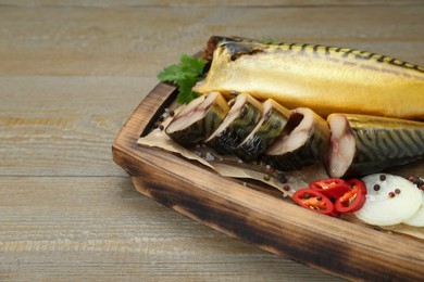 Photo of Delicious smoked mackerels with pepper, onion and spices on wooden table, closeup. Space for text