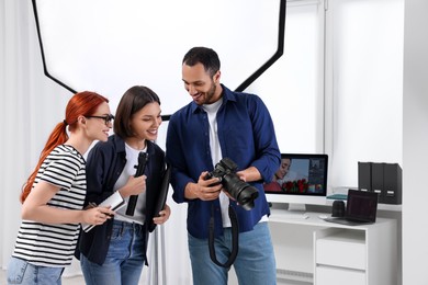 Photo of Young professional photographers working in modern photo studio, space for text