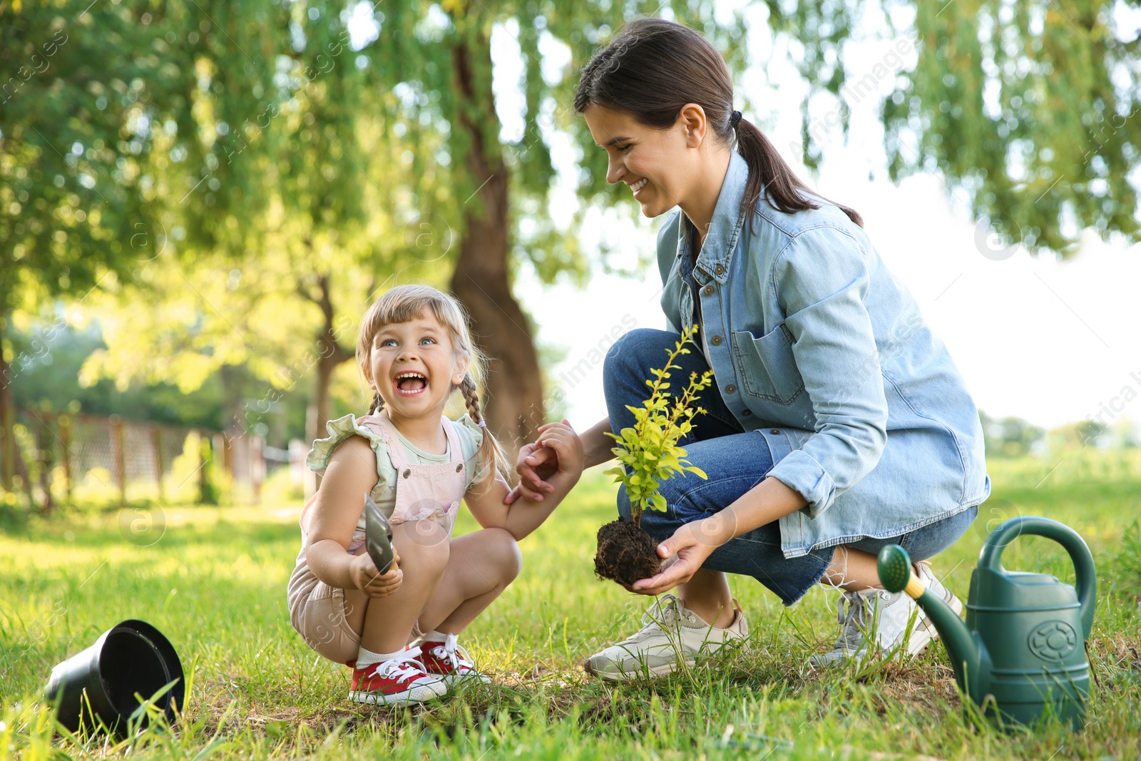 Photo of Mother and her daughter planting tree together in garden