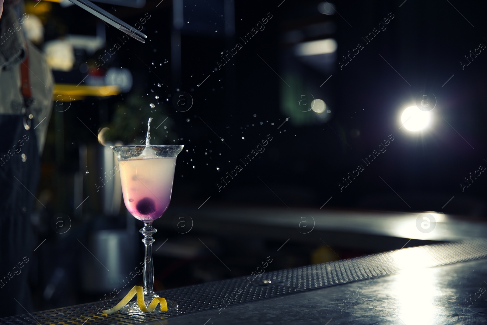 Photo of Barman adding cherry into cosmopolitan martini cocktail at counter, closeup. Space for text