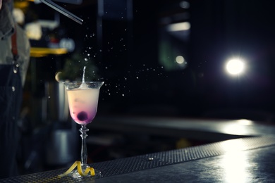 Photo of Barman adding cherry into cosmopolitan martini cocktail at counter, closeup. Space for text