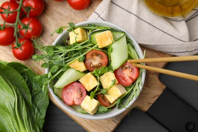 Photo of Tasty salad with tofu and vegetables near ingredients on grey wooden table, flat lay
